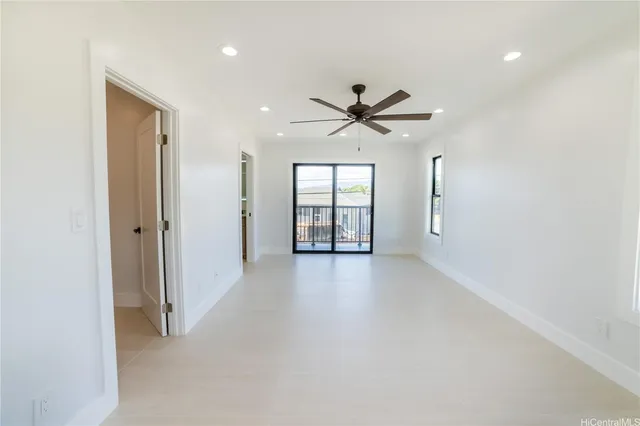 an empty room with windows and ceiling fan
