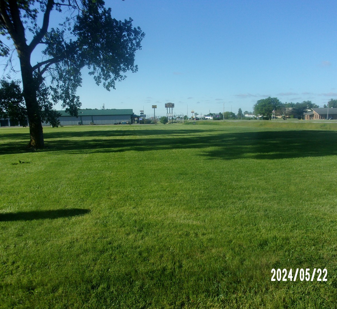 a yard with lots of green space and trees in the background
