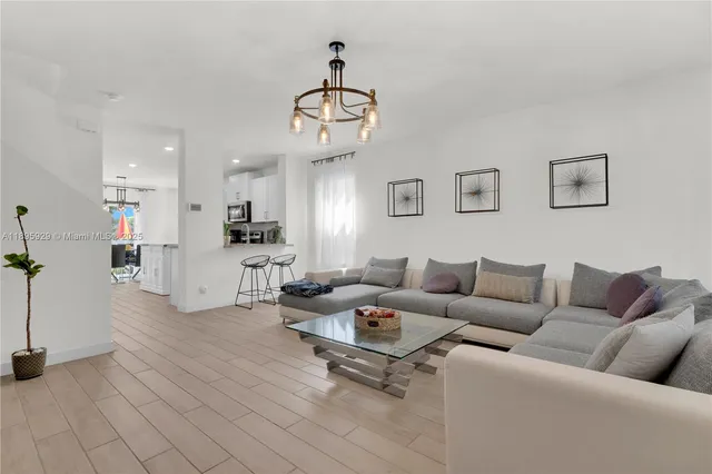 a living room with furniture kitchen view and a chandelier