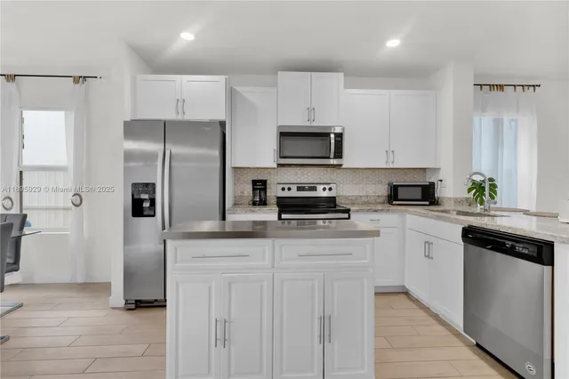 a kitchen with white cabinets and stainless steel appliances