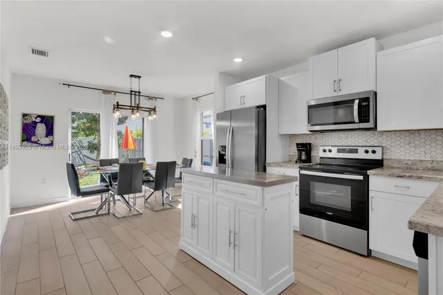 a kitchen with stainless steel appliances a stove a sink refrigerator and a microwave