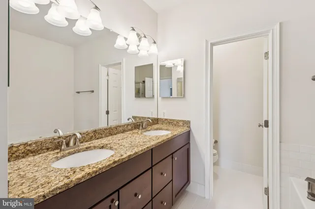a bathroom with a granite countertop sink a mirror and a bathtub