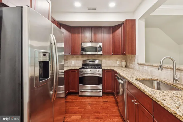 a kitchen with granite countertop a refrigerator and a stove top oven