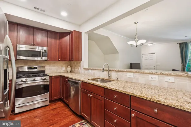 a kitchen with kitchen island granite countertop stainless steel appliances a sink stove top oven and cabinets