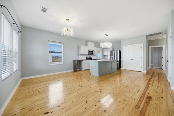 a view of kitchen and empty room with wooden floor