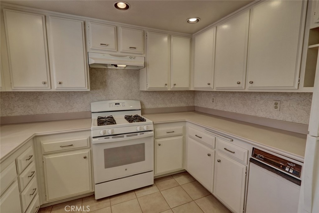 8566 Larkhall Circle, Unit 808A Huntington Beach, CA 92646 - Photo 14 of 46 a kitchen with white cabinets and white appliances