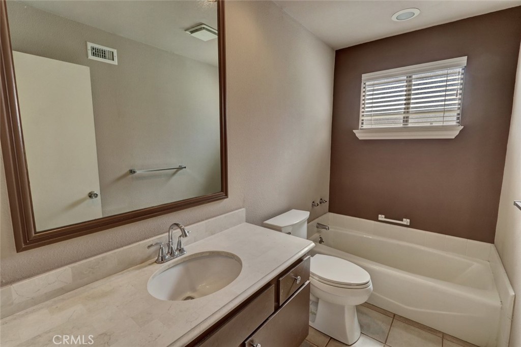 8566 Larkhall Circle, Unit 808A Huntington Beach, CA 92646 - Photo 27 of 46 a bathroom with a granite countertop sink toilet a mirror and shower