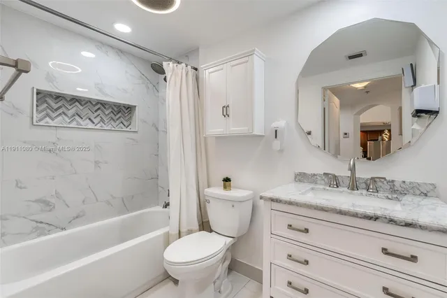 a bathroom with a granite countertop sink toilet mirror and bathtub