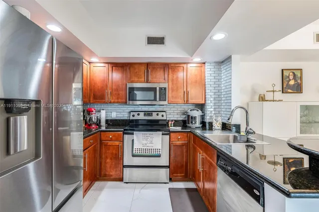 a kitchen with stainless steel appliances granite countertop a sink stove microwave and refrigerator