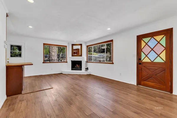 a view of an empty room with a window and wooden floor
