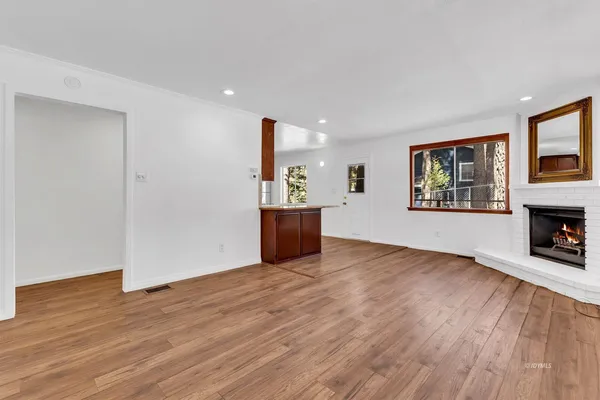 a view of empty room with wooden floor and fireplace