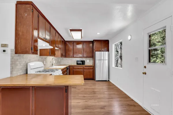 a kitchen with stainless steel appliances granite countertop a sink a stove a refrigerator cabinets and wooden floor