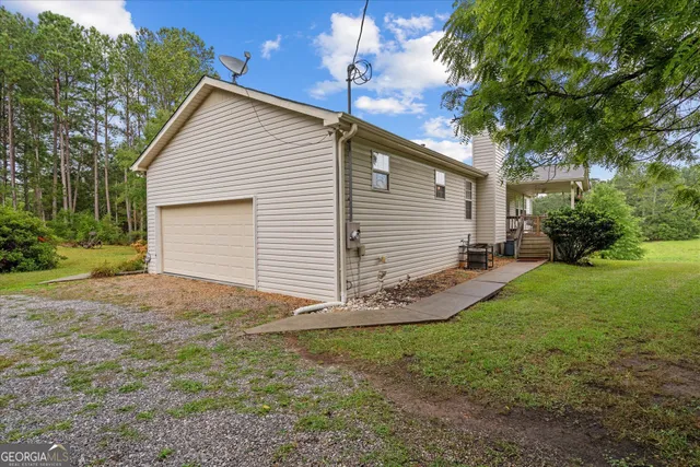 a backyard of a house with plants and large tree