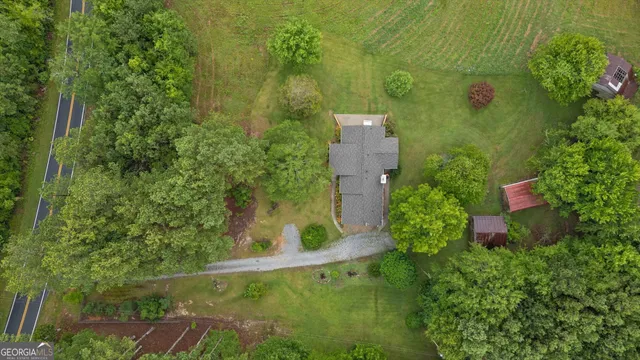 an aerial view of residential house with outdoor space and trees all around