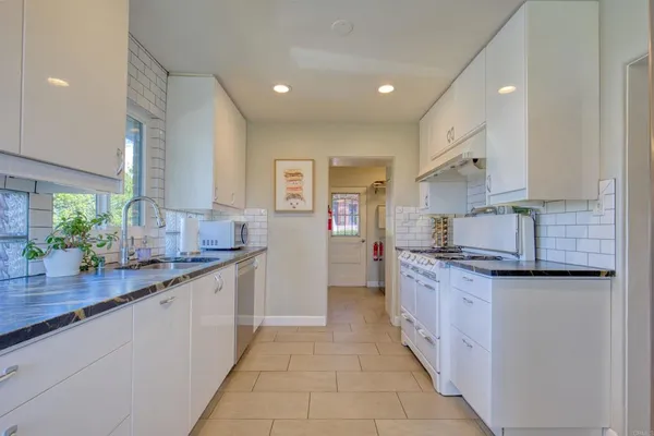 a kitchen with granite countertop white cabinets and white appliances