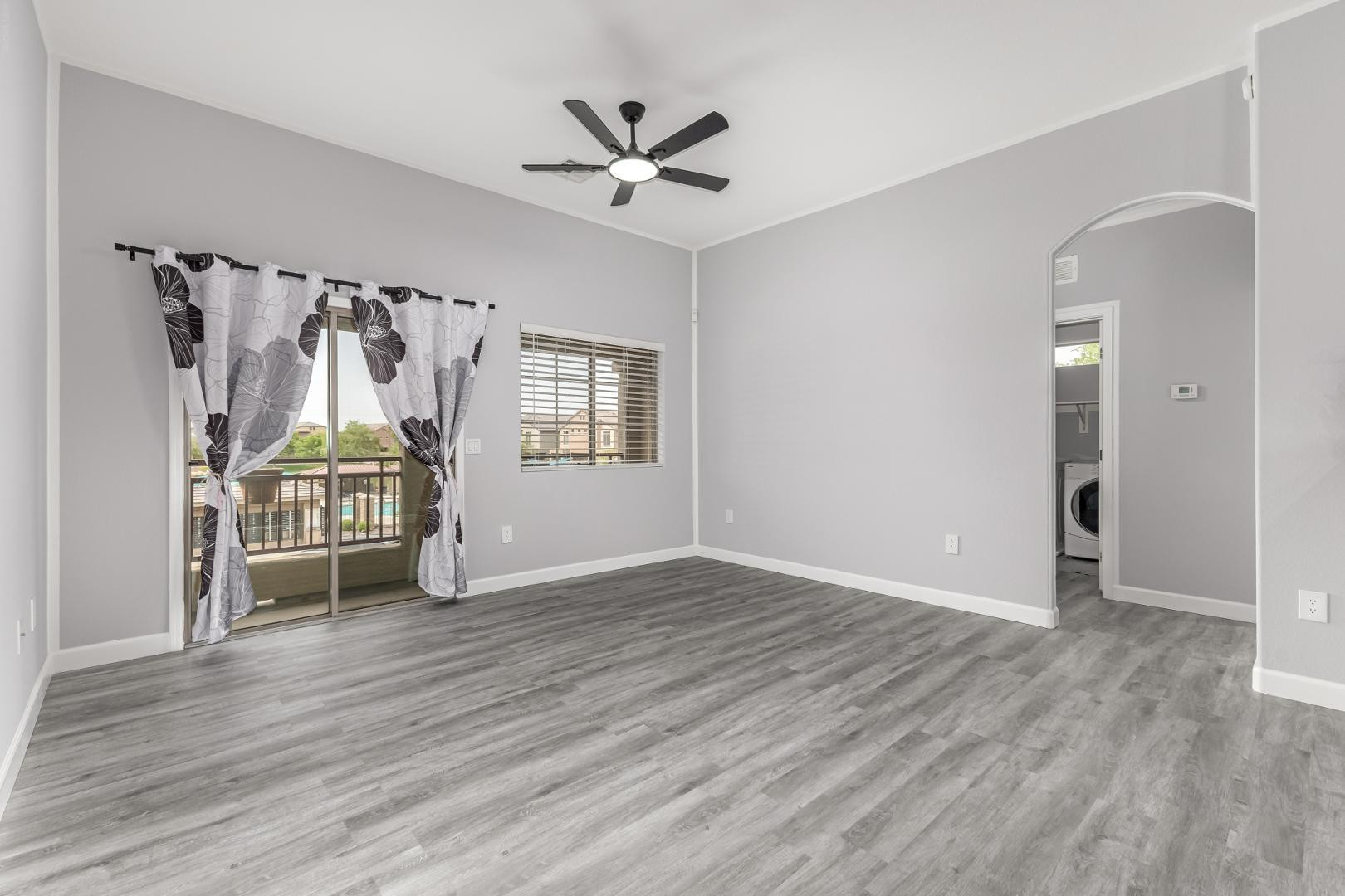 1350 South Greenfield Road, Unit 2205 Mesa, AZ 85206 - Photo 6 of 42 an empty room with wooden floor a ceiling fan and windows
