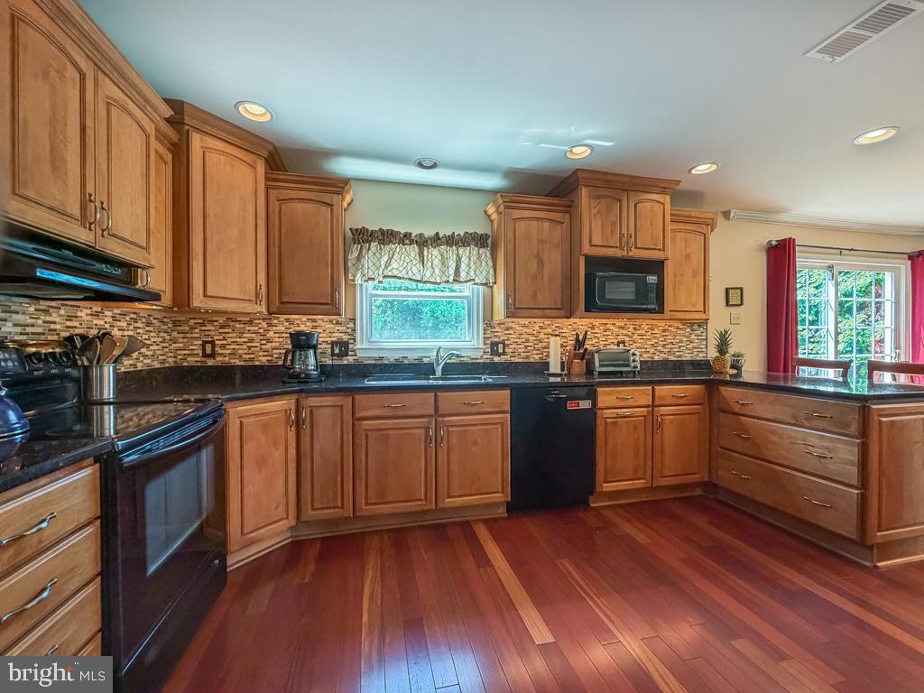 925 Big Oak Road Yardley, PA 19067 - Photo 17 of 51 a kitchen with stainless steel appliances granite countertop wooden cabinets a stove a sink and dishwasher with wooden floor