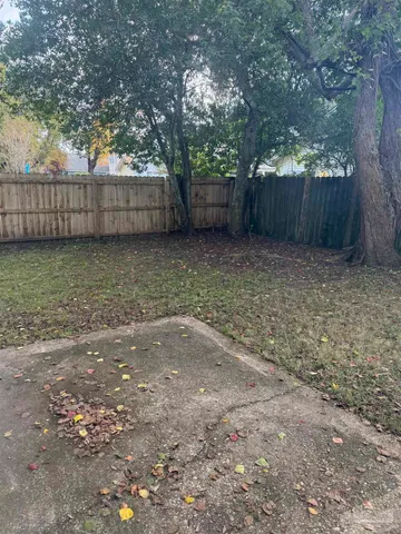 a view of backyard with wooden fence and a large tree