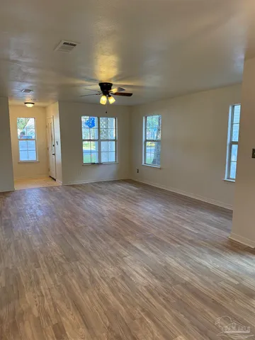 an empty room with wooden floor and windows