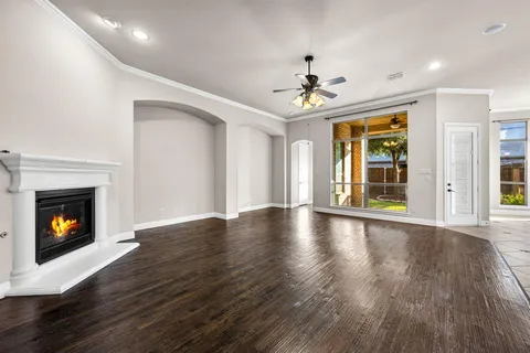 a view of an empty room with wooden floor fireplace and a window