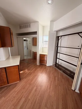 a view of an empty room with wooden floor and stairs