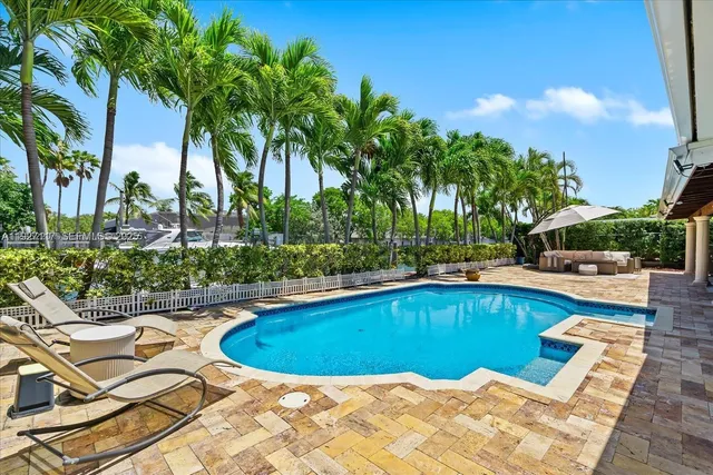 a view of a swimming pool with a lounge chair and palm trees