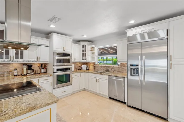 a kitchen with stainless steel appliances granite countertop a refrigerator and a stove top oven