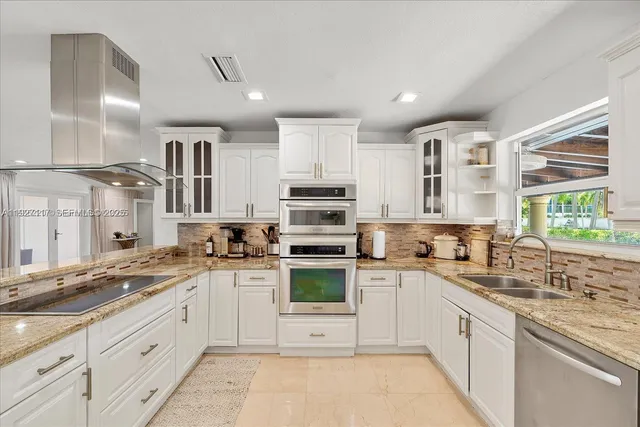 a kitchen with stainless steel appliances granite countertop a stove sink and cabinets