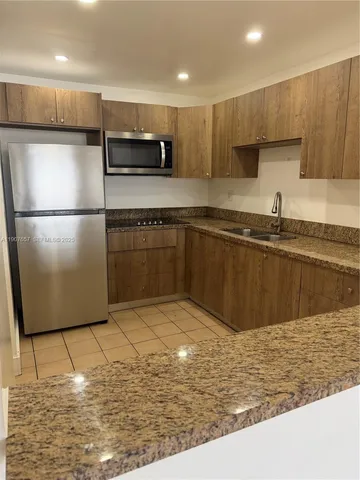 a kitchen with stainless steel appliances granite countertop a refrigerator a sink a stove a microwave and island