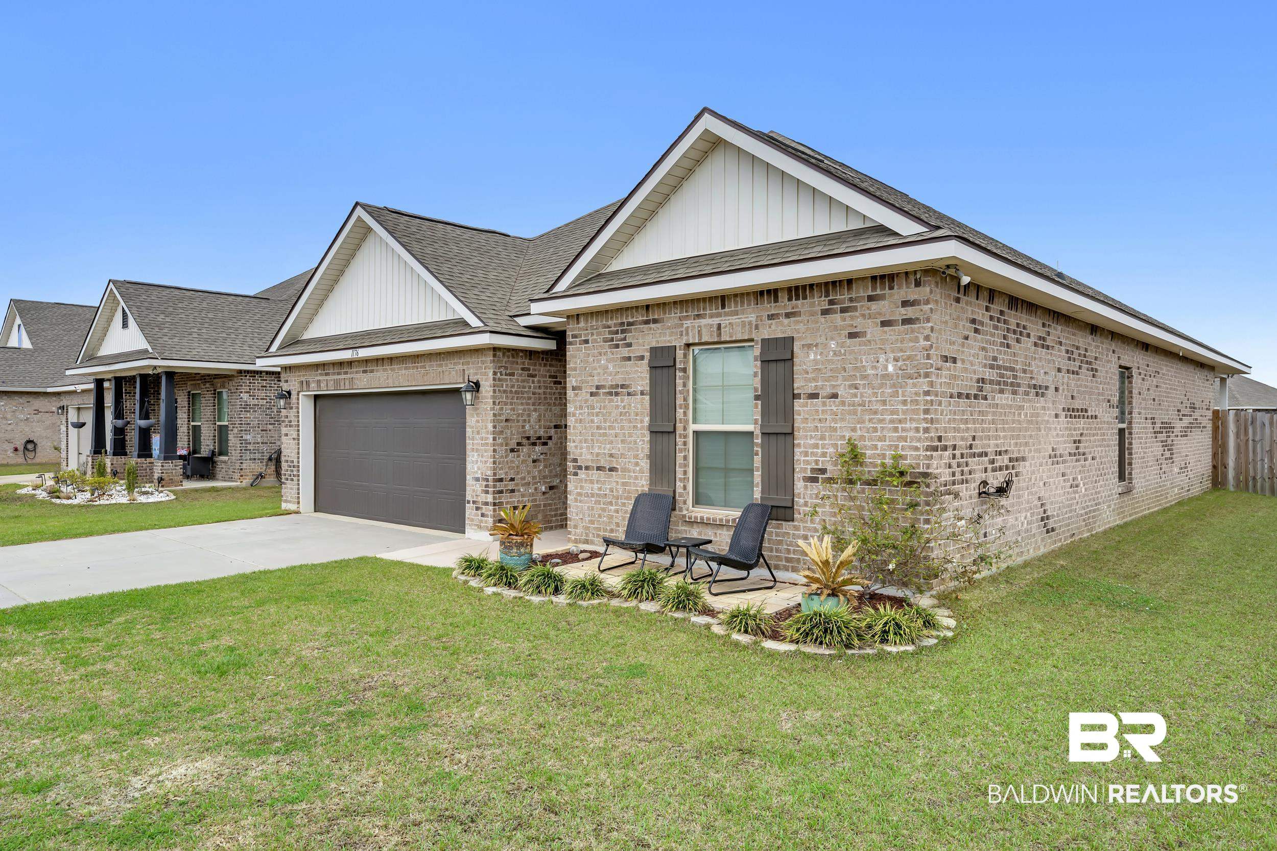 1176 Stella Road Foley, AL 36535 - Photo 4 of 40 View of front of house featuring a front lawn, brick siding, driveway, a garage, and a shingled roof