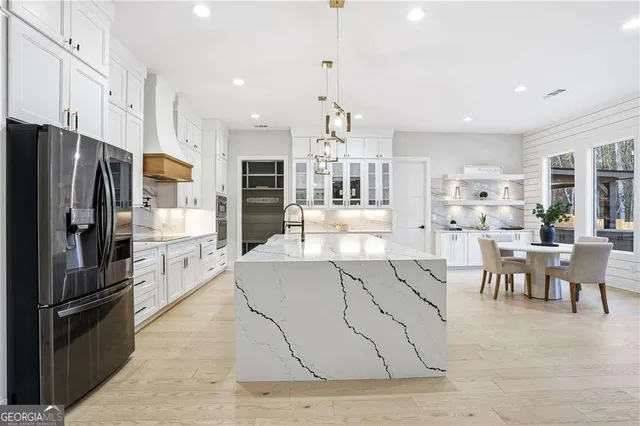 a kitchen with stainless steel appliances kitchen island granite countertop a refrigerator a stove a sink a dining table and chairs with wooden floor
