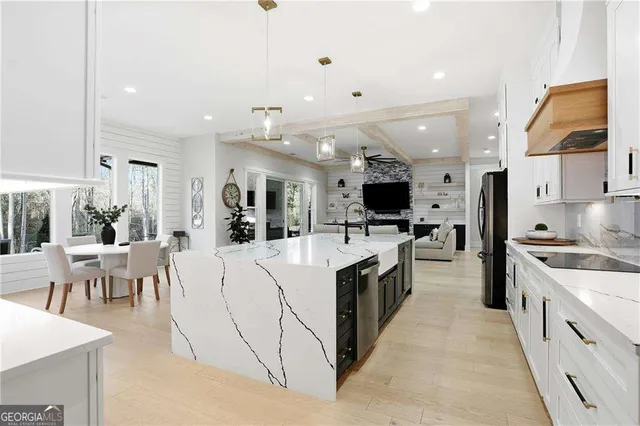 a large open kitchen with stainless steel appliances kitchen island a stove a refrigerator a dining table and chairs with wooden floor