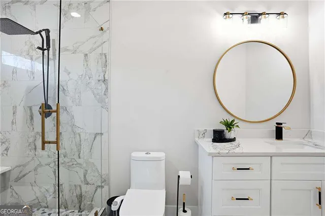 a bathroom with a granite countertop sink mirror vanity and toilet