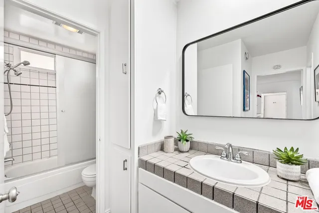 a bathroom with a granite countertop sink mirror and a shower
