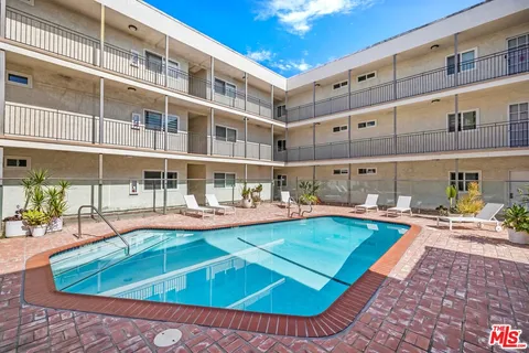 a view of a swimming pool with a lounge chairs in front of a house