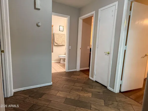 a view of an empty room with wooden floor and a bathroom
