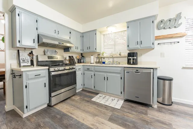 a kitchen with stainless steel appliances a sink a stove a refrigerator and cabinets