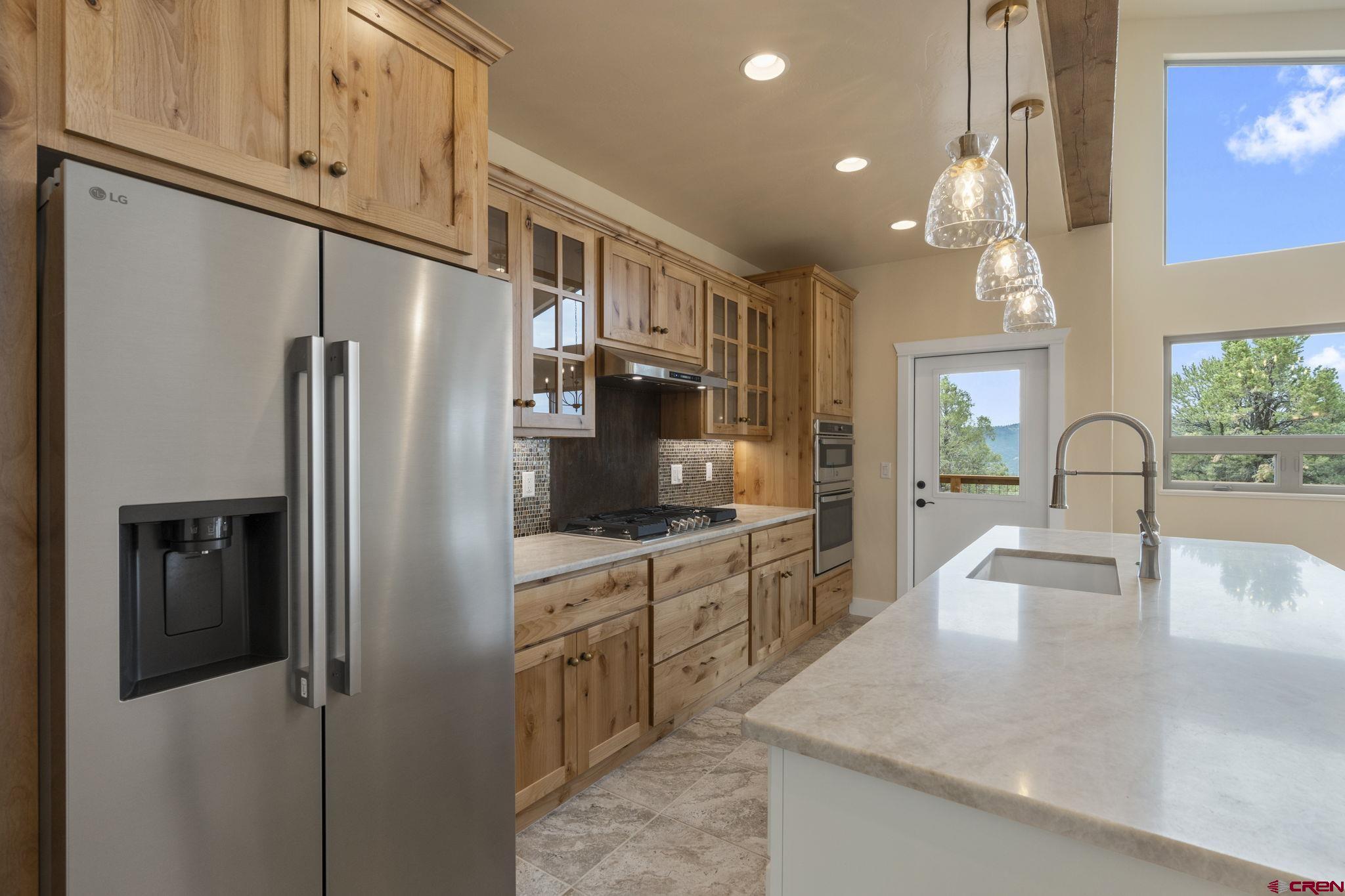 640 Sawmill Road Durango, CO 81303 - Photo 12 of 42 a kitchen with stainless steel appliances granite countertop a refrigerator a stove and a sink with wooden floor