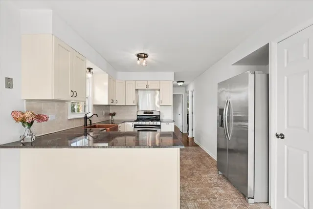 a kitchen with granite countertop a refrigerator a sink a stove and cabinets