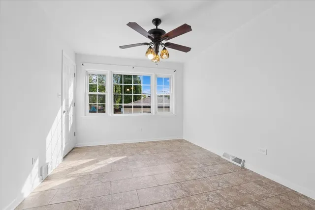 an empty room with ceiling fan and windows