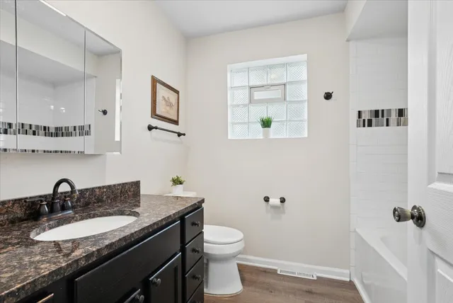 a bathroom with a granite countertop sink a toilet and a mirror