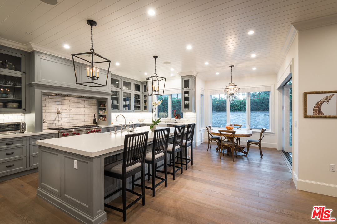 222 20th Street Santa Monica, CA 90402 - Photo 7 of 44 a kitchen with stainless steel appliances granite countertop a stove top oven a sink a dining table and chairs with wooden floor