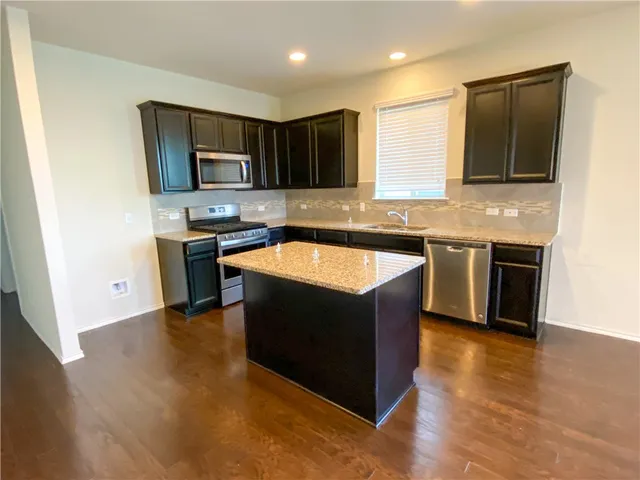 a kitchen with stainless steel appliances granite countertop a stove a sink and a microwave