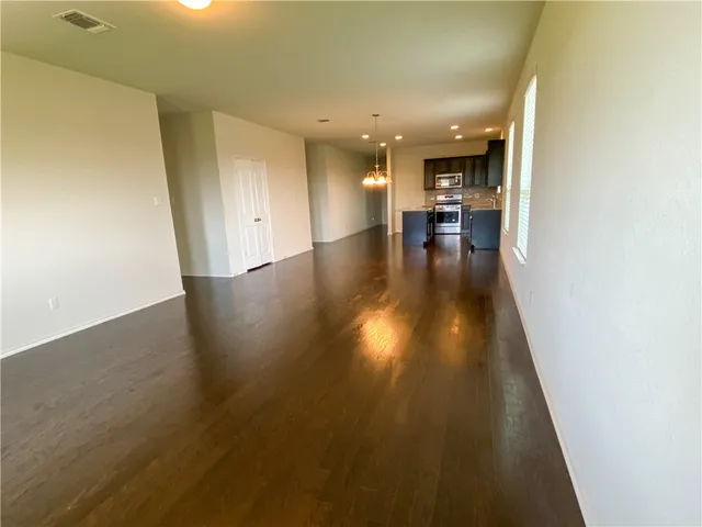 a view of a hallway view with wooden floor and a kitchen space