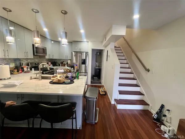 a kitchen with stainless steel appliances kitchen island granite countertop a sink and wooden floor