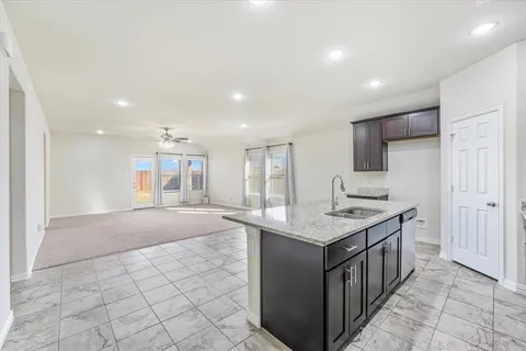 a kitchen with kitchen island granite countertop a sink and a stove top oven