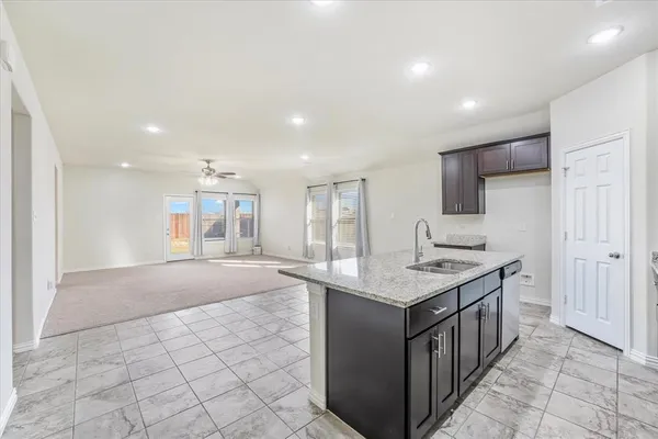 a kitchen with kitchen island granite countertop a sink and a stove top oven