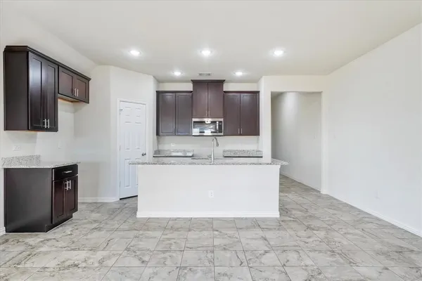 a large white kitchen with kitchen island granite countertop a sink and a stove top oven