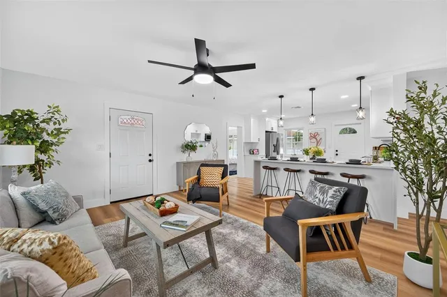 a kitchen with a refrigerator a stove a sink and a dining table with wooden floor