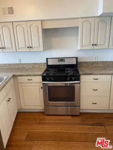 a kitchen with granite countertop white cabinets and stainless steel appliances